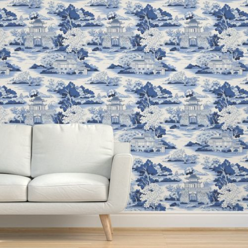 A white couch against a wall with wall art for living room featuring Large Blue Chinoiserie wallpaper from Stannie & Lloyd, including pagoda designs.