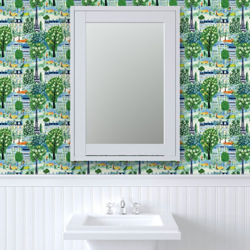 A bathroom wall with Spring in Paris wallpaper above white wainscoting, featuring a mounted mirror above a sink and art prints by Stannie & Lloyd.