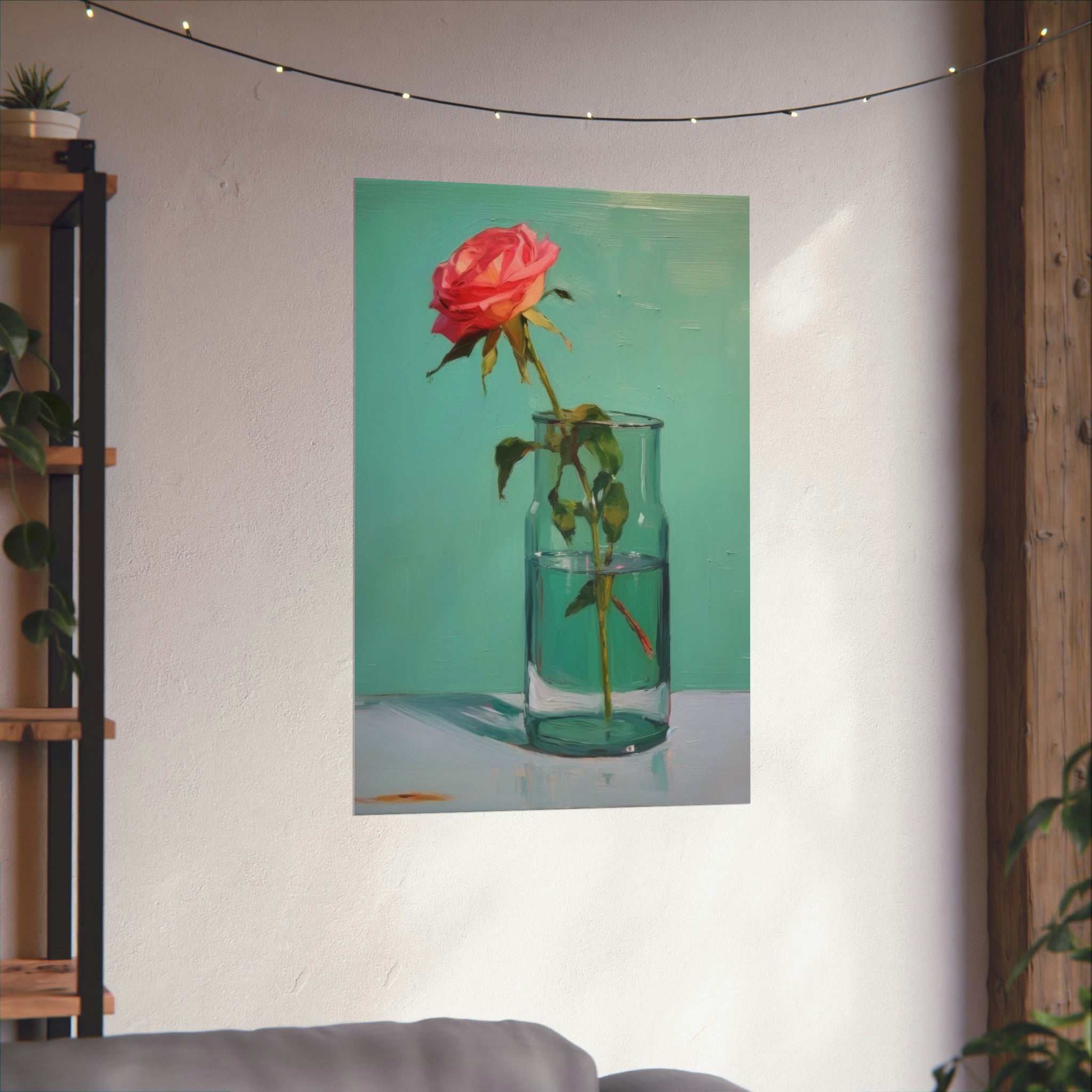 A framed vintage art of a rose in a Glass of Water in Greens hanging on a wall, adorned with string lights and adjacent to a plant shelf. (Printify)