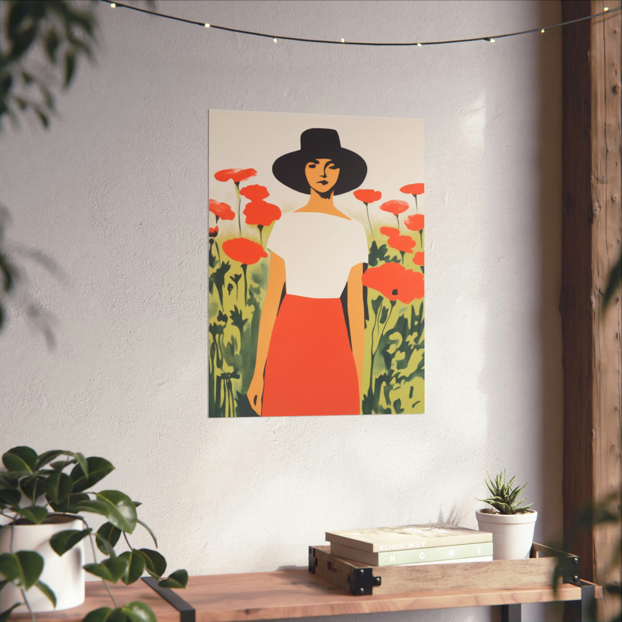 A framed vintage art illustration of a woman in a hat standing in a field of poppies, displayed on walls above a wooden table with plants featuring "The Long Gaze" poster from Printify in large matte format and available in 3 sizes.