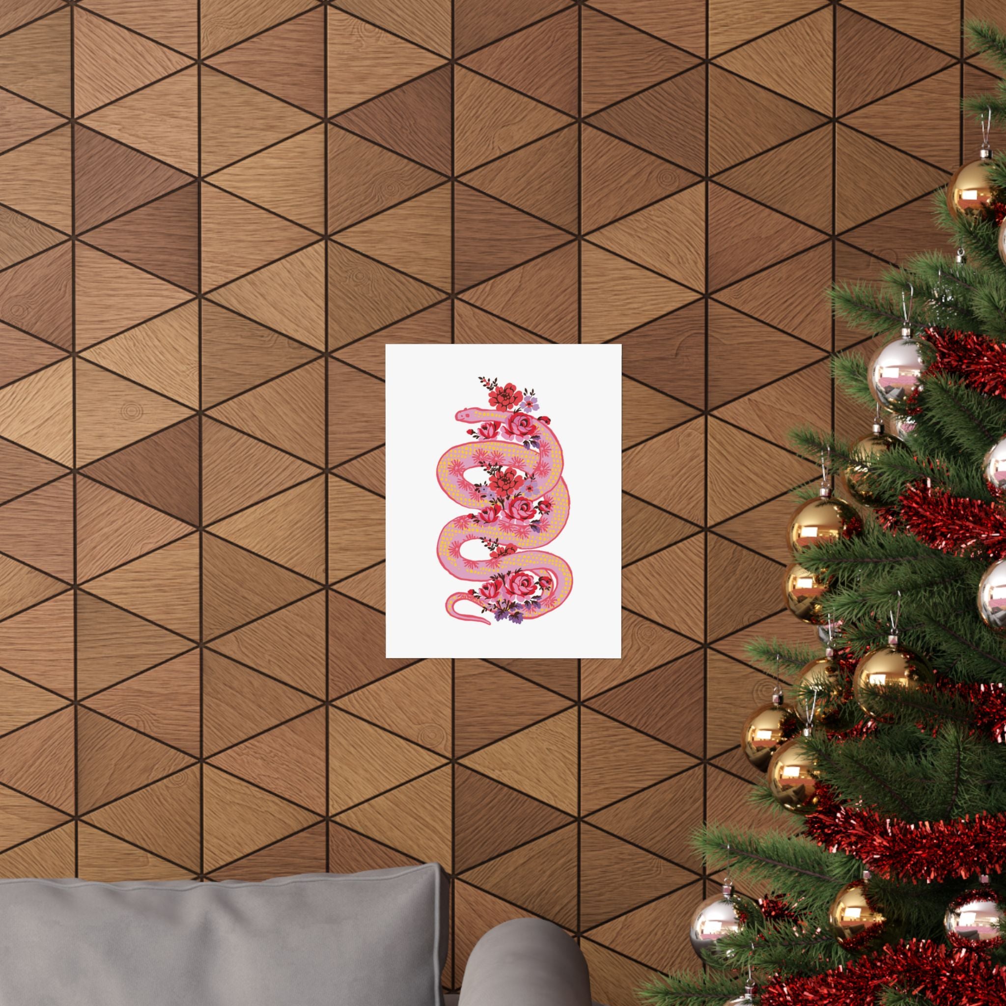 A geometric wood-paneled wall displays the "Snake with Roses" large matte poster by Printify; a decorated Christmas tree and part of a gray sofa appear in the foreground.
