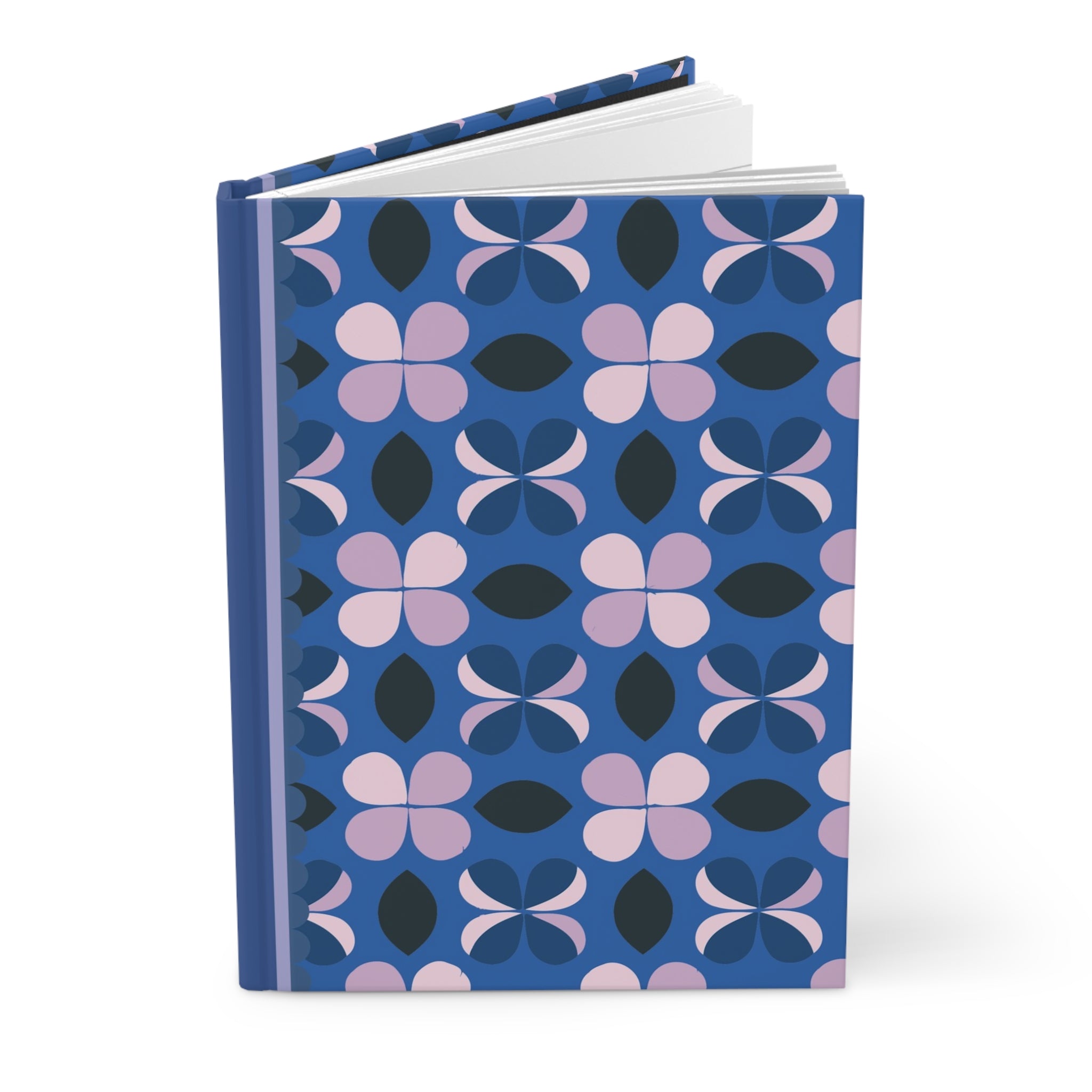 A customizable "Hardcover Journal Matte" by Printify featuring a blue cover with a repetitive pattern of pink and black geometric flowers. The notebook, adorned with a matte finish, is standing upright and partially open.