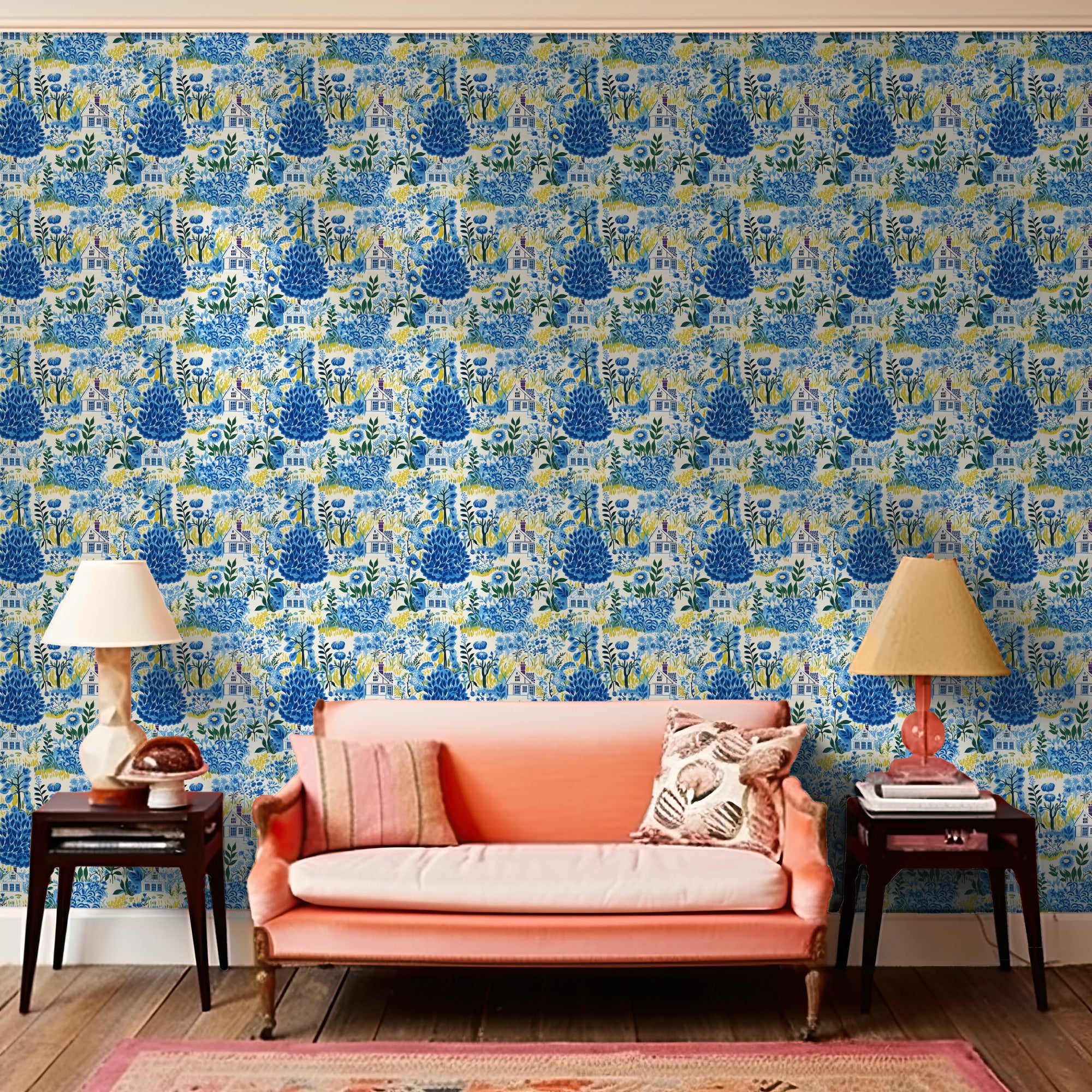 A living room with a Cozy Cottage in Blue wallpaper by Stannie & Lloyd, flanked by two wooden side tables and table lamps.