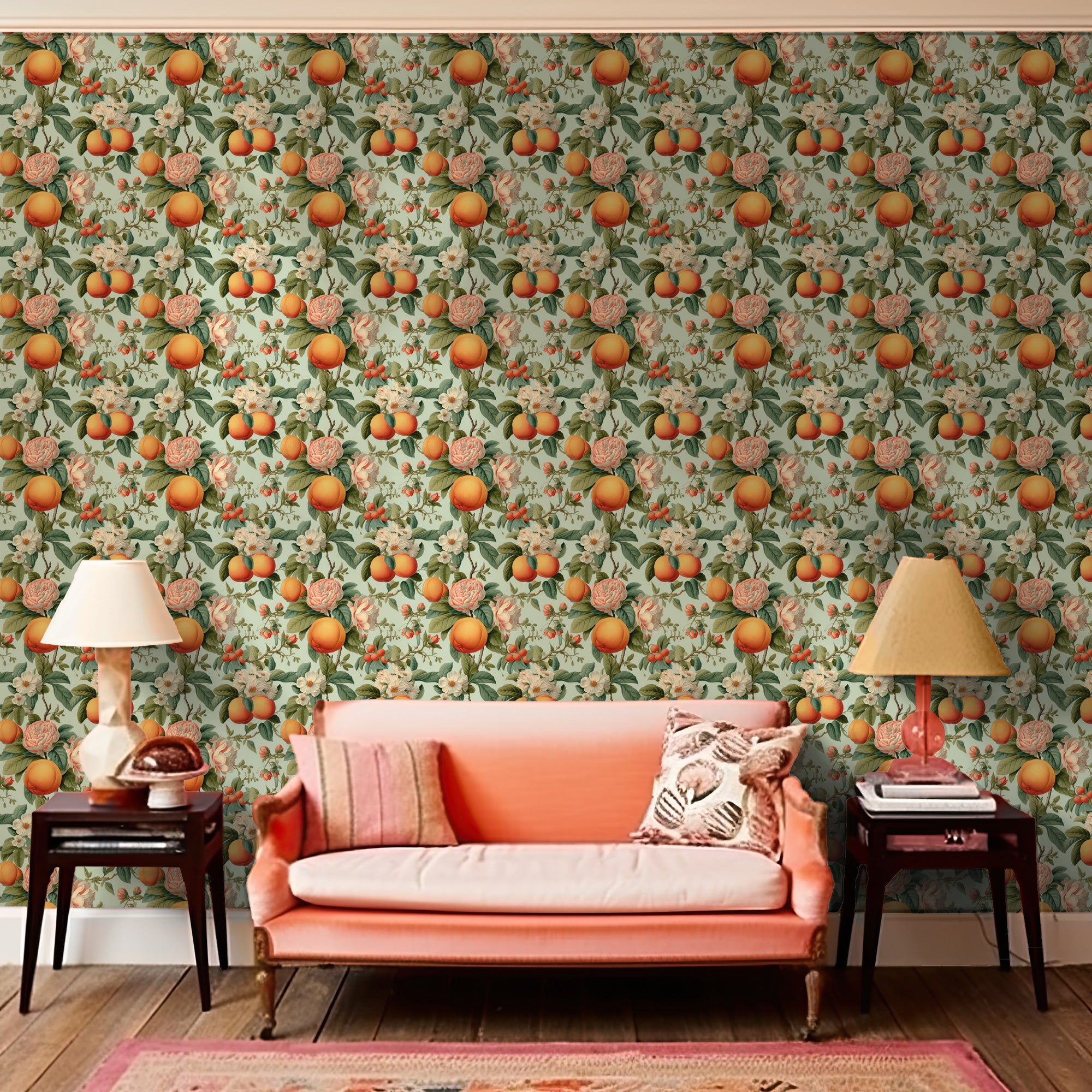 A living room with an orange-themed decor, featuring Vintage Orange Blossoms wallpaper on the walls, a peach-colored sofa, and matching table lamps from Stannie & Lloyd.