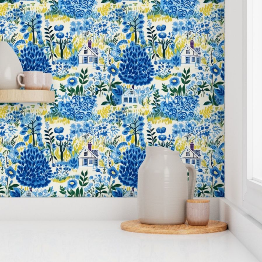 Bright floral and pastoral-themed Cozy Cottage in Blue wallpaper by Stannie & Lloyd in a kitchen with a ceramic jug and cup on the countertop.