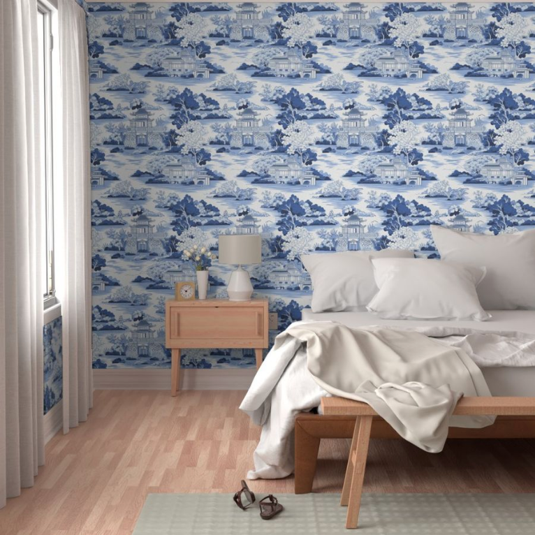 A neatly made bed with white bedding in a room with a Large Blue Chinoiserie Wallpaper from Stannie & Lloyd, wooden furniture, and wall art for living room.