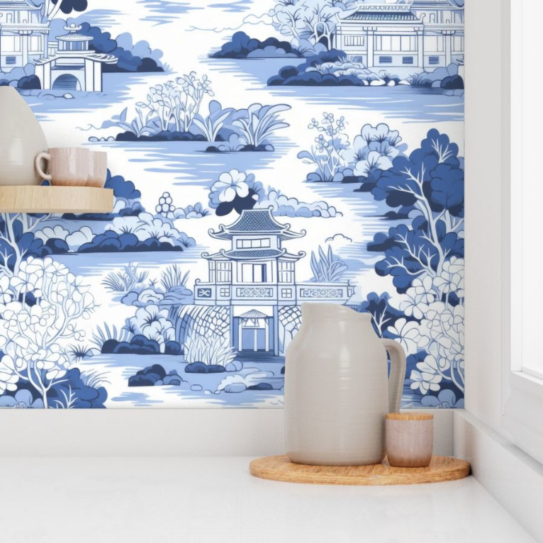 A ceramic jug and cups on a wooden tray against a backdrop of Large Blue Chinoiserie Wallpaper from Stannie & Lloyd with wall art for living room.