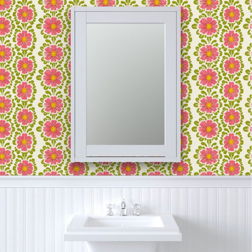 Rectangular mirror above a white sink against a Pink Pop Flowers Wallpaper by Stannie & Lloyd with art prints.