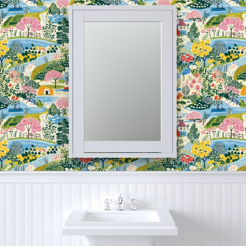 A bathroom with a white pedestal sink and a rectangular mirror mounted on wall decor with Colorful Cozy Village Wallpaper from Stannie & Lloyd.