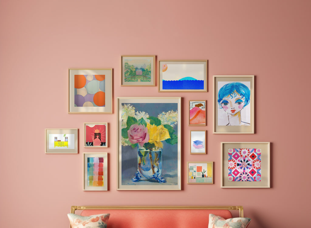 A collection of framed art on a pink wall.